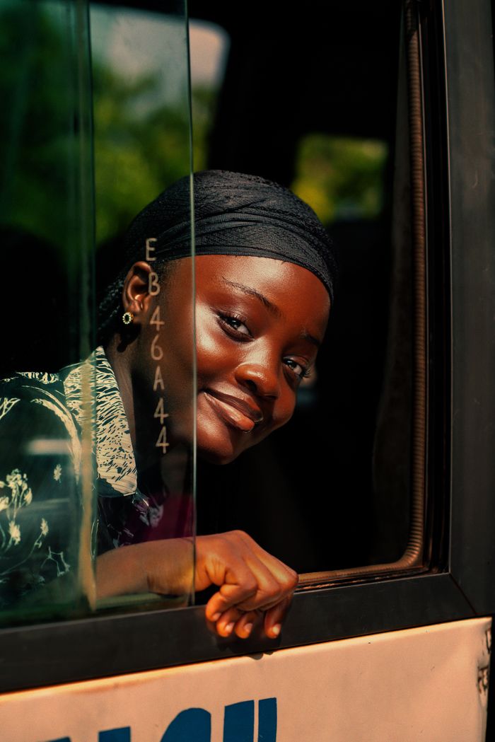 Smiling woman in a vehicle gazing outside on a sunny day.